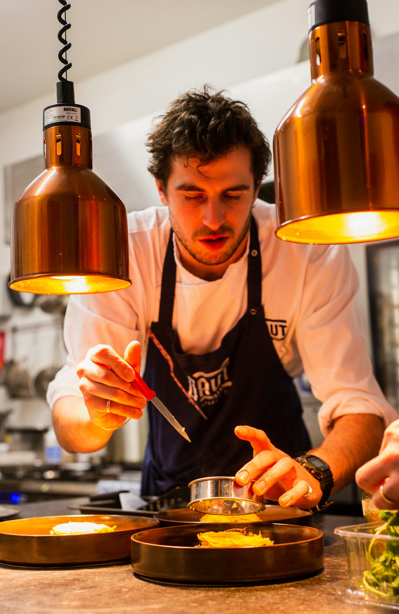 A chef plating a dish in the Helm and Honey kitchen